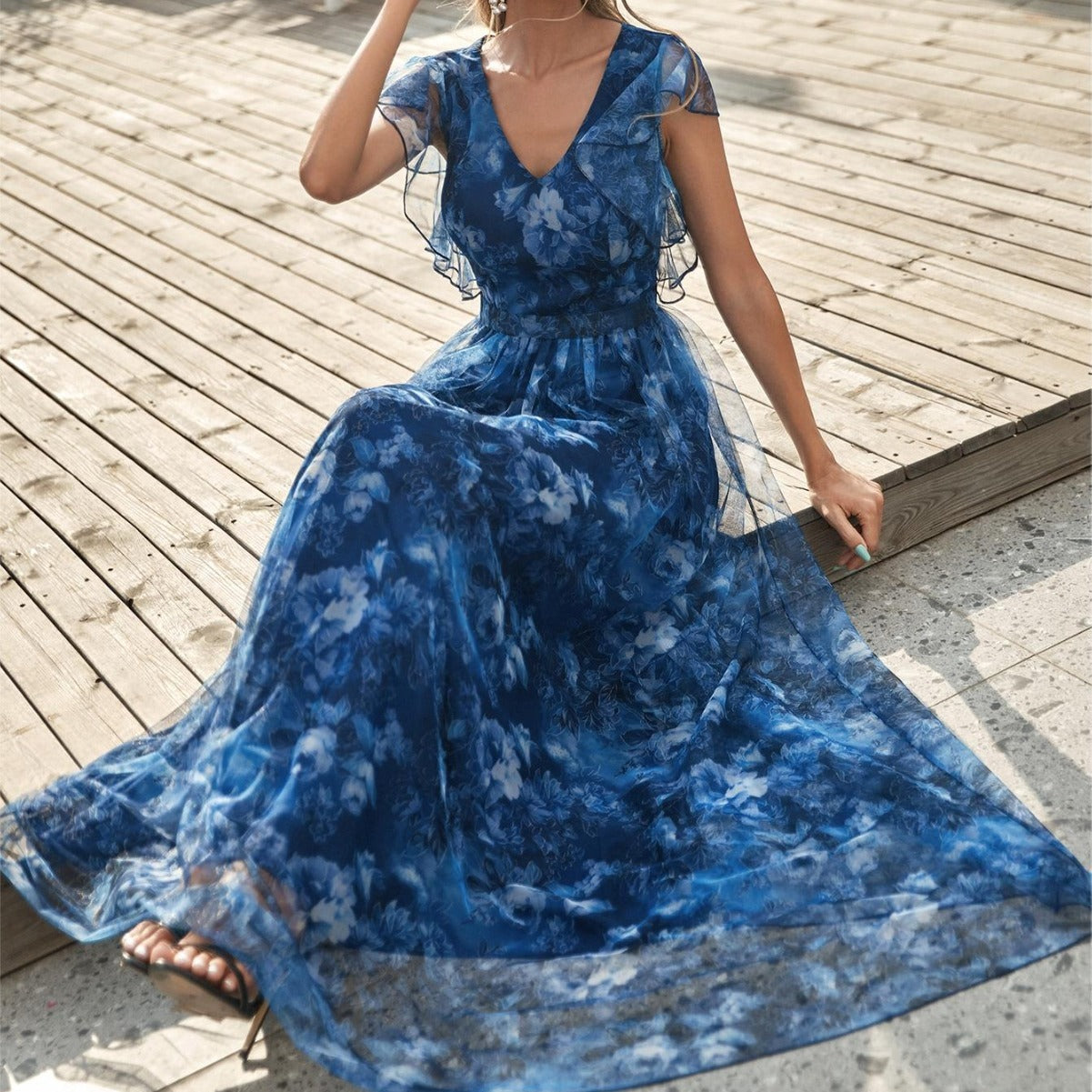 Woman wearing a blue floral dress on a wooden deck