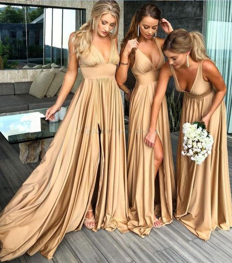 Three women in beige long dresses standing outdoors.