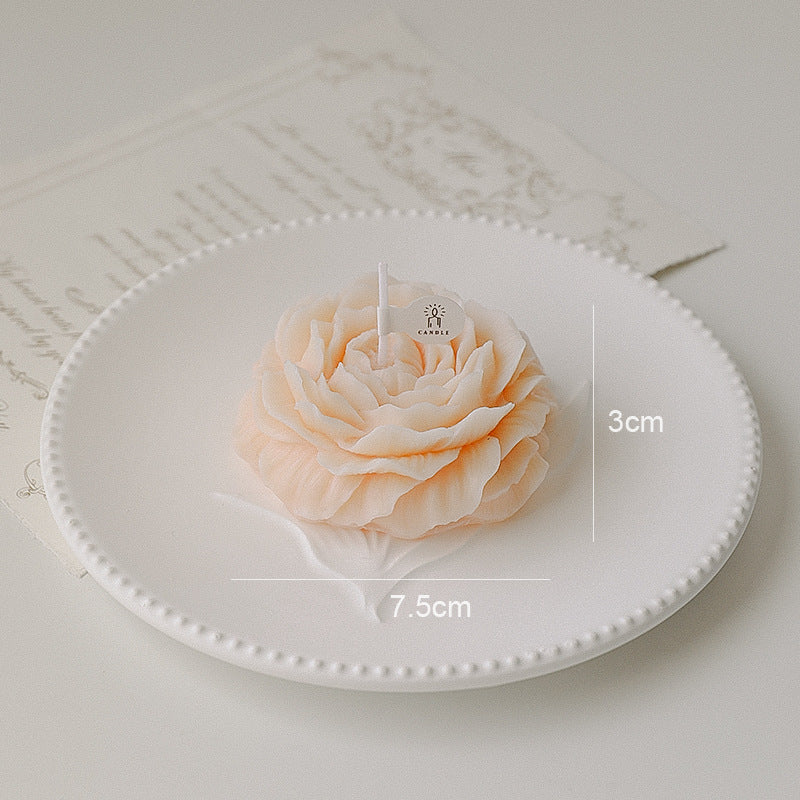 Decorative candle shaped like a rose on a white plate with measurements indicated.