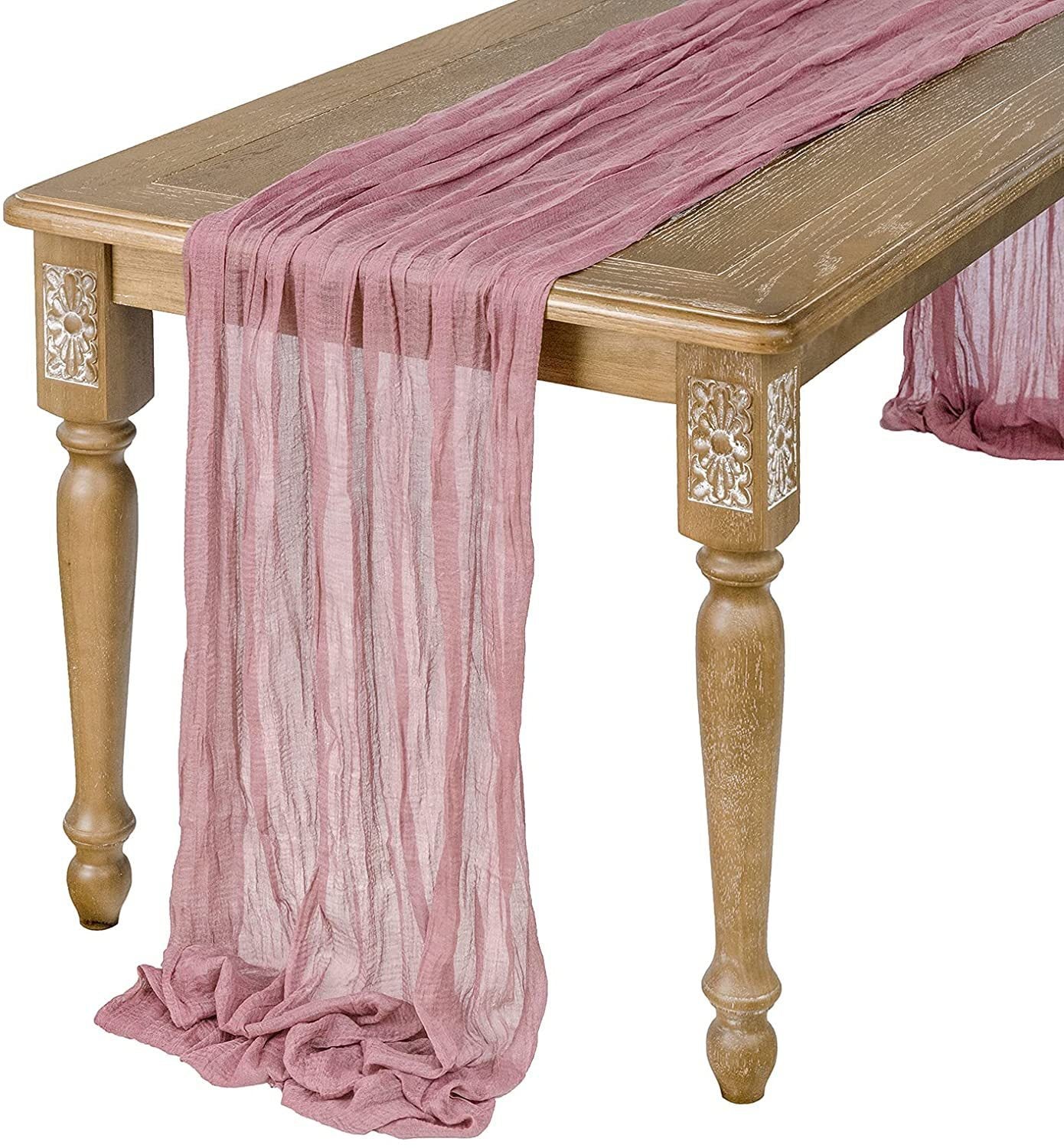 Pink table runner draped over a wooden table with decorative carvings.