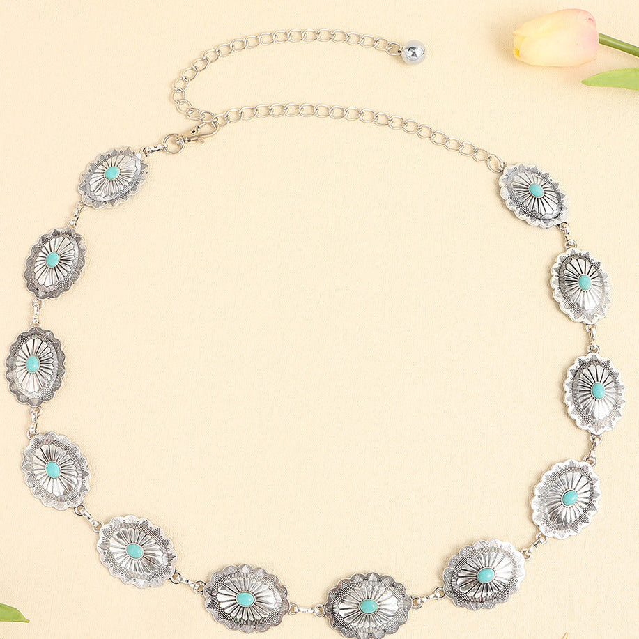 Silver necklace with concho-like designs on a light beige background