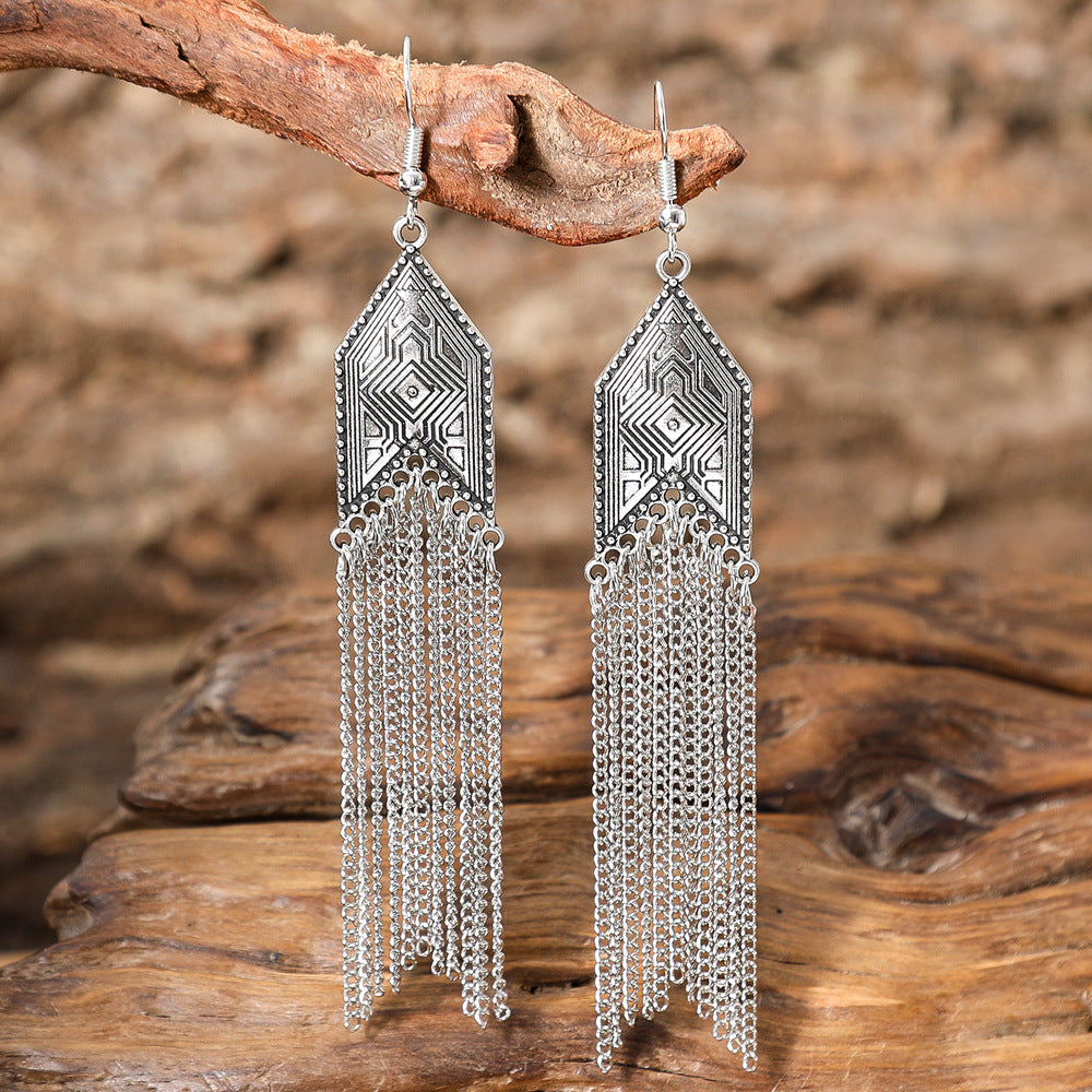Silver chain earrings on a wooden branch with a natural background