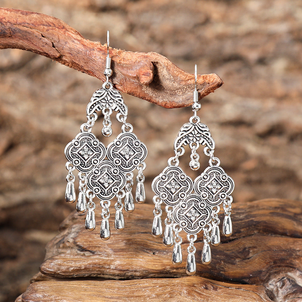 Silver chandelier earrings on a wooden branch with a natural background