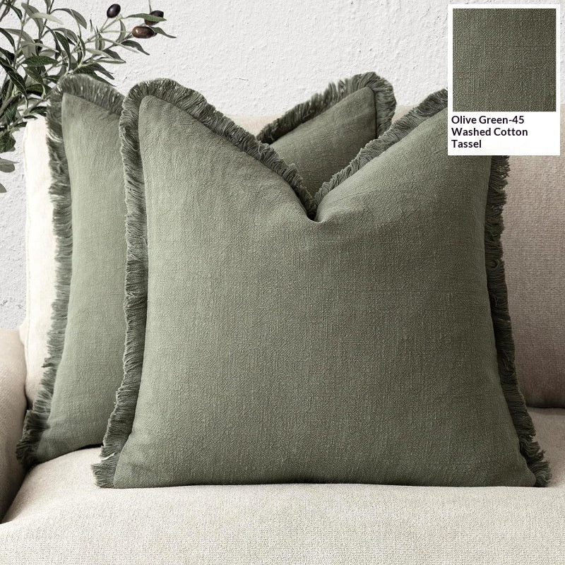 Green textured pillow with tassel on a sofa, labeled Olive Green-45 Washed Cotton Tassel.