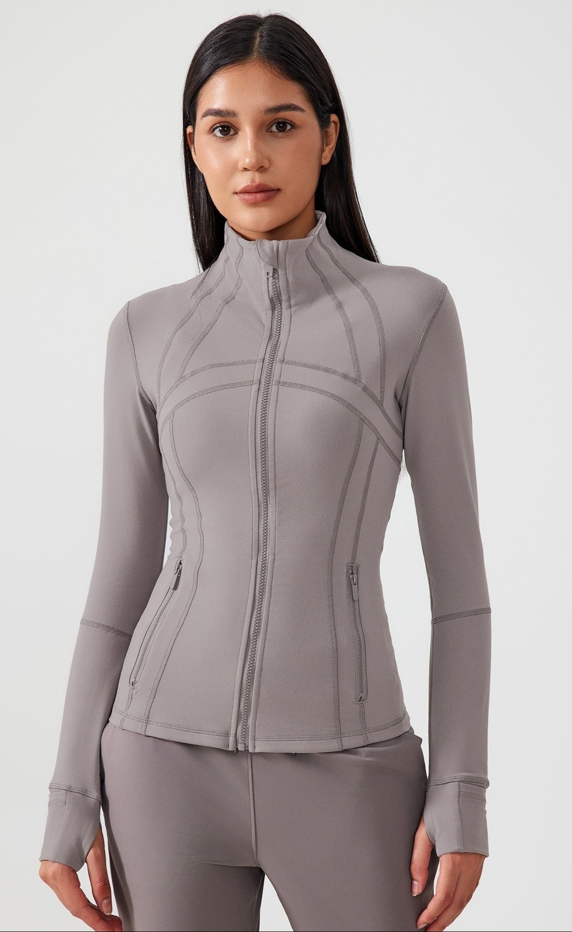Woman wearing a gray athletic jacket and pants on a white background