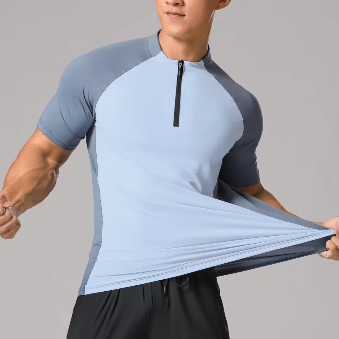Person wearing a gray and light blue athletic shirt with a zipper, holding it out to show fabric.