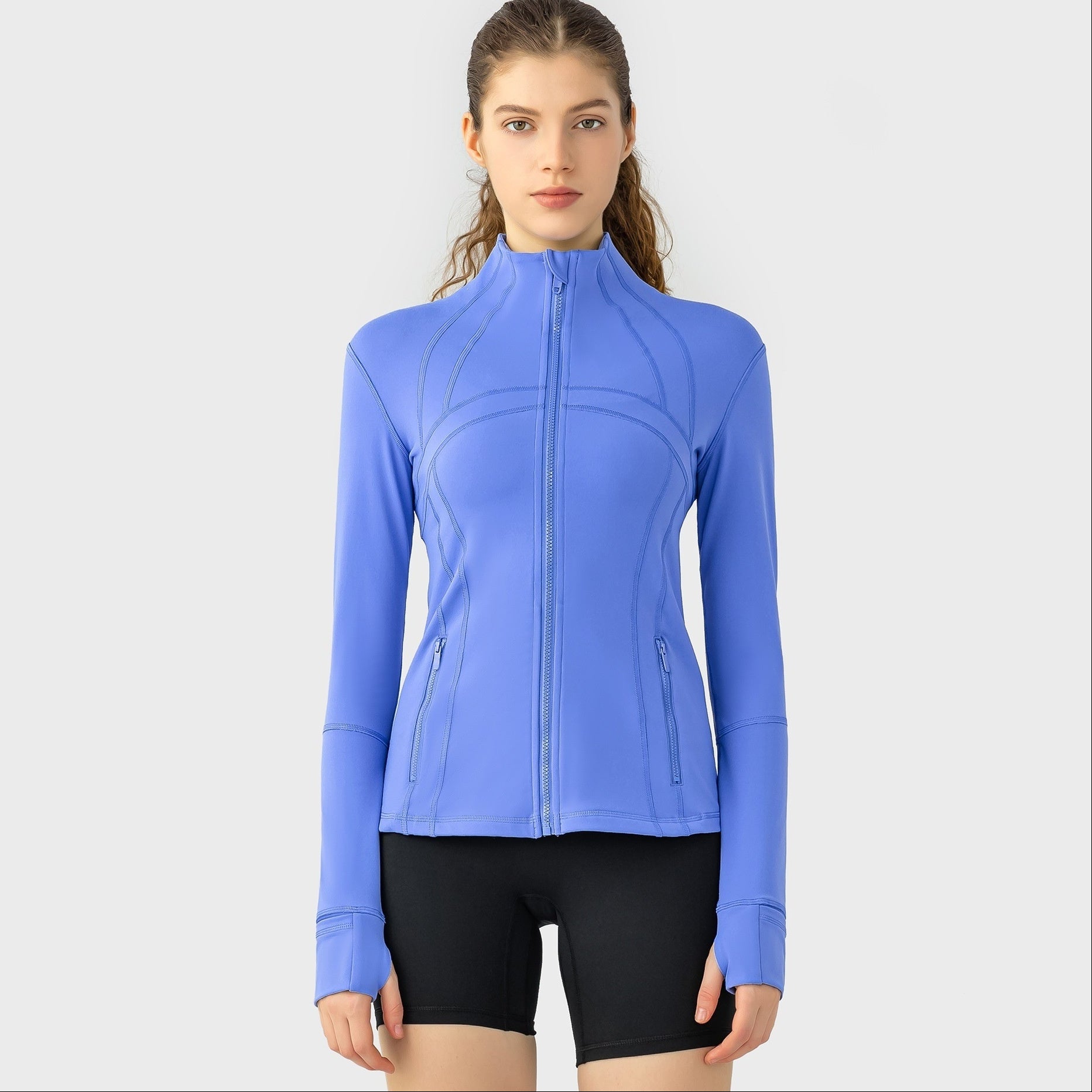 Woman wearing a blue athletic jacket and black shorts on a white background