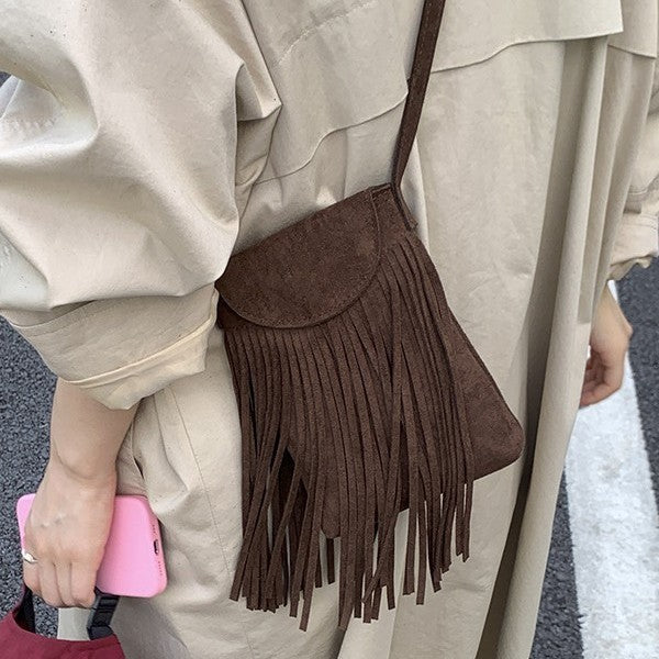 Brown fringed handbag worn over shoulder with beige coat