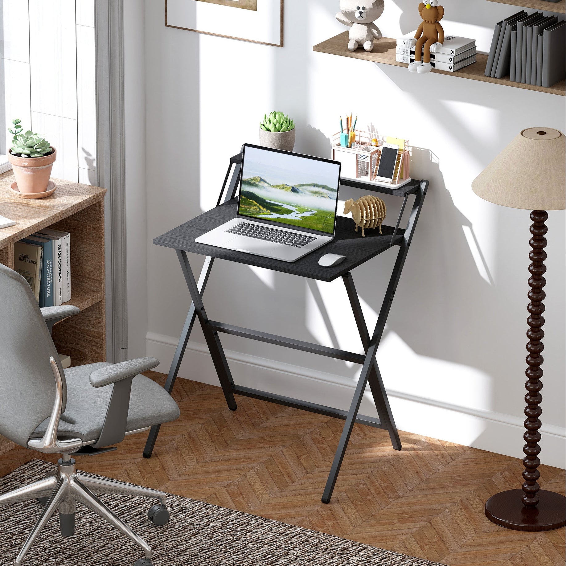 Home office with a laptop on a black folding desk, chair, and decor items.
