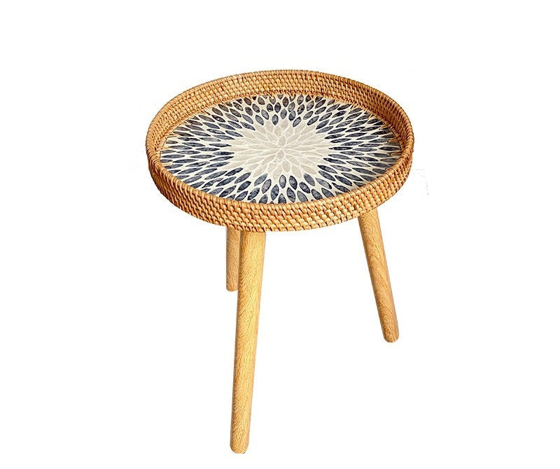 Round woven side table with a decorative top on a white background