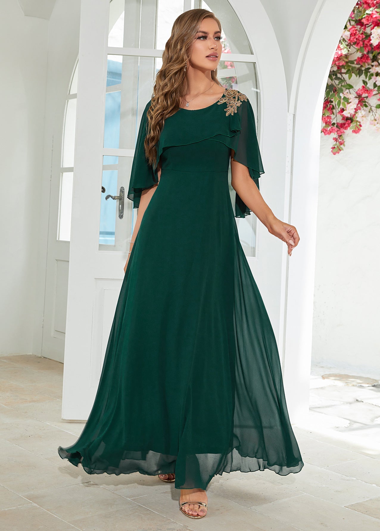 Woman wearing a green dress with a floral headband in a bright room.