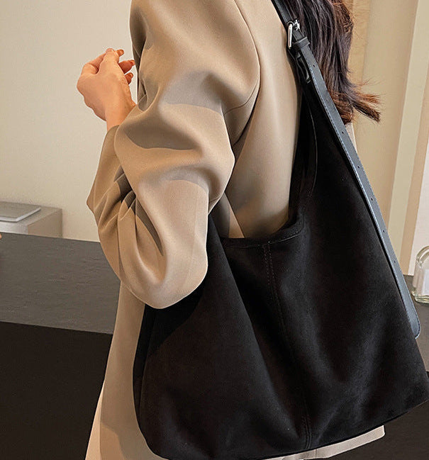 Person holding a black handbag with bottles in the background