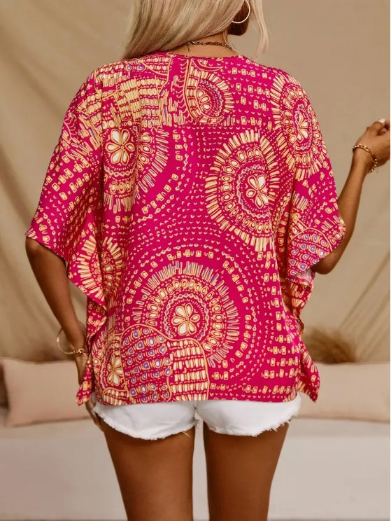 Person wearing a pink and orange patterned top with white shorts on a neutral background