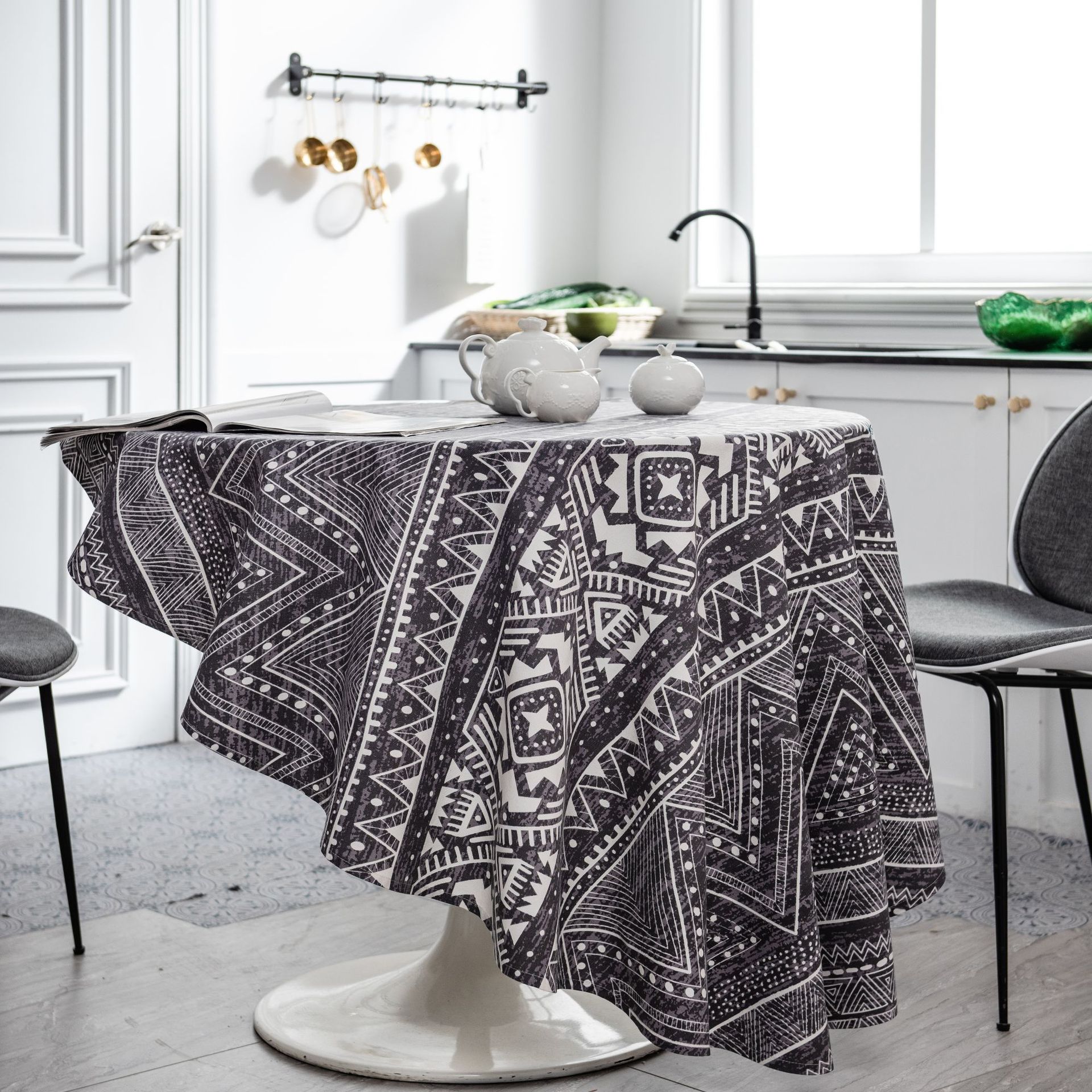 Table with a black and white patterned tablecloth in a kitchen setting.