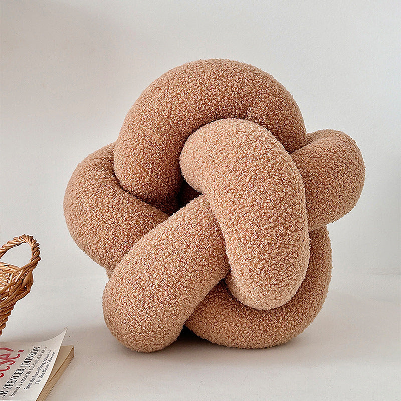 Textured knot pillow on a light surface with a neutral background