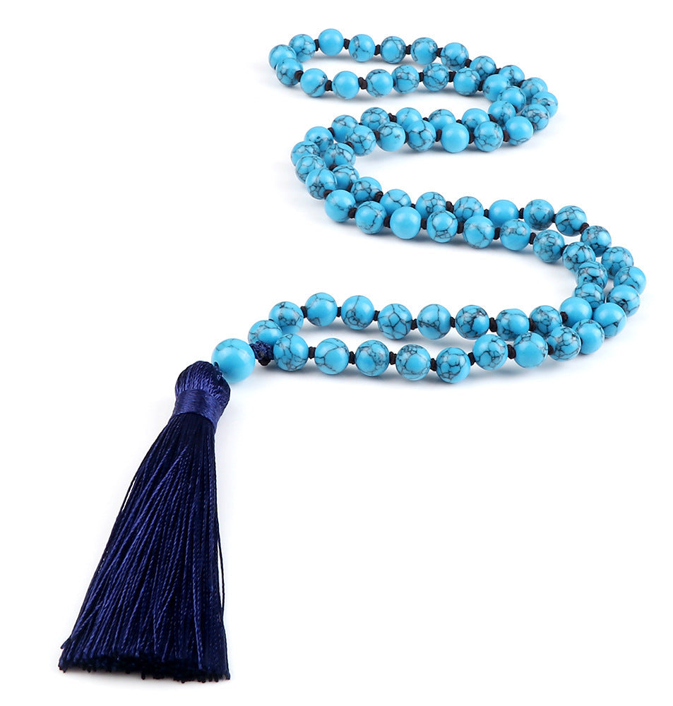Turquoise beaded necklace with a blue tassel on a white background