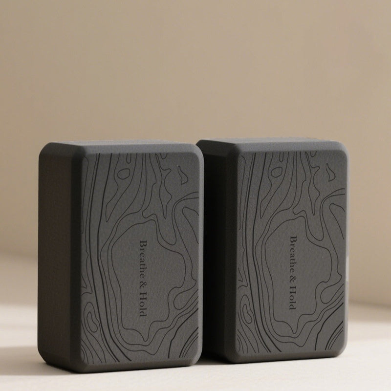 Two black yoga blocks with 'Breathe & Hold' text on a beige background