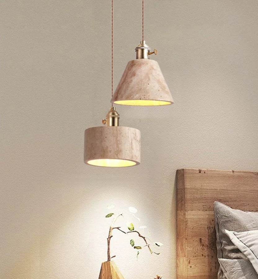 Two concrete pendant lights hanging above a bed with a neutral wall background.