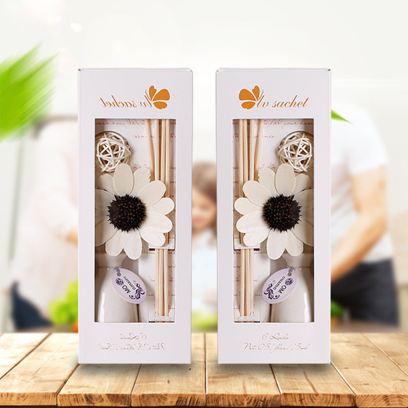 Two diffuser sets with floral designs in white boxes on a wooden surface.