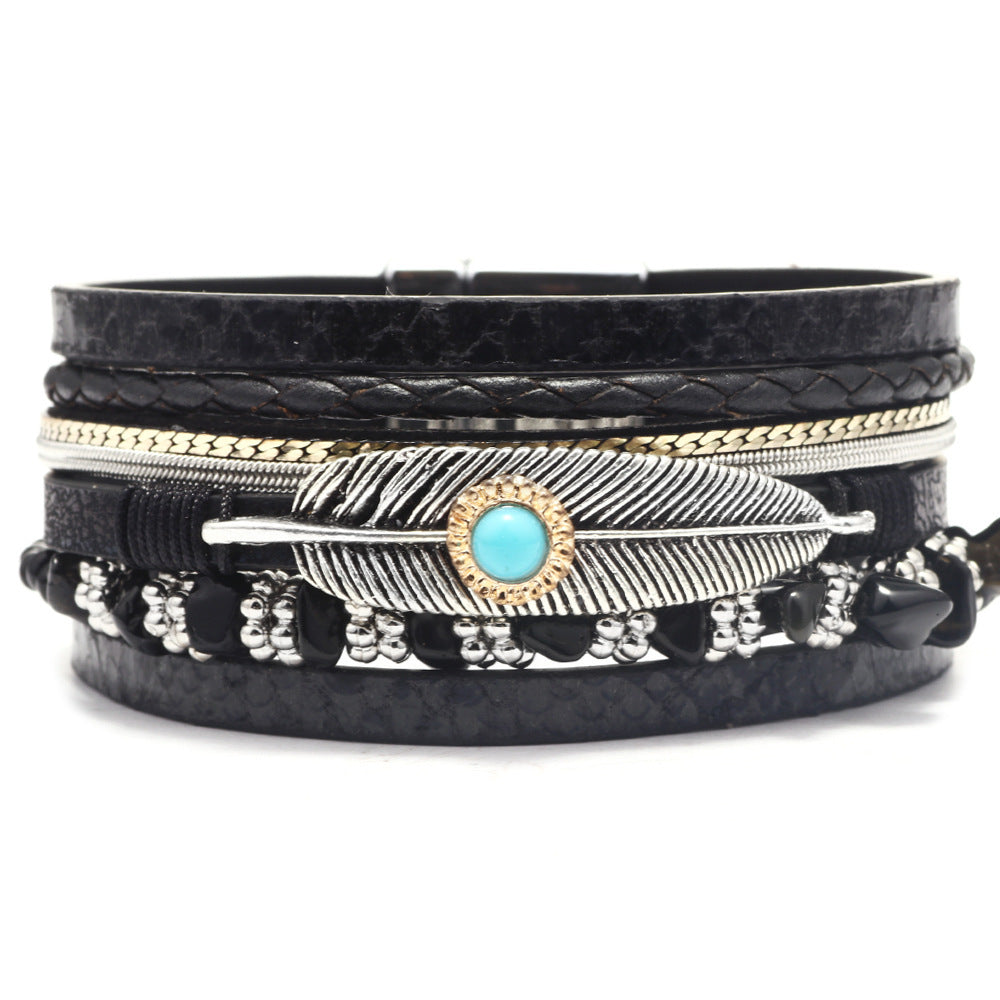 Black leather wrap bracelet with feather and turquoise stone design on a white background