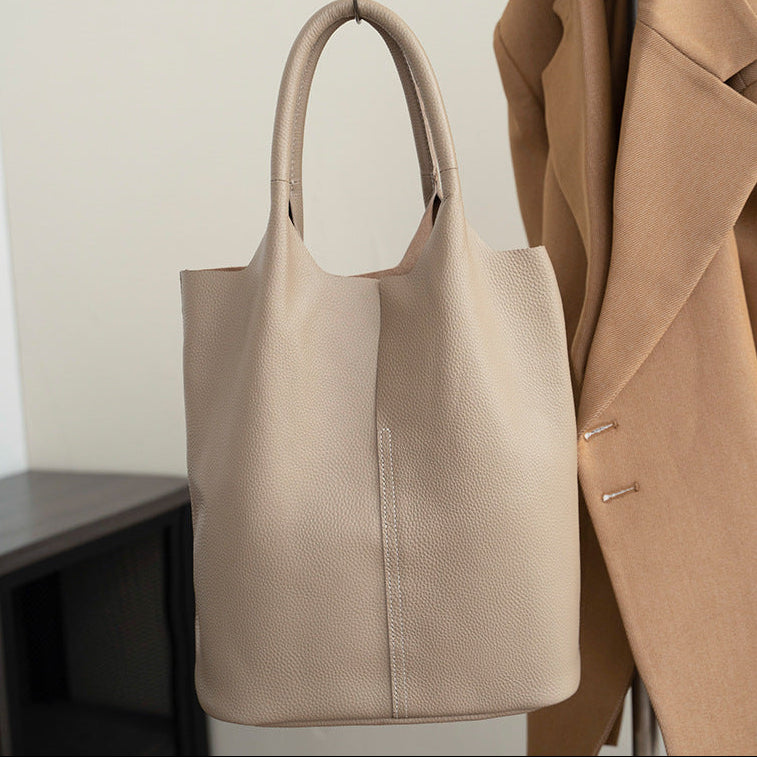 Beige handbag hanging on a hook next to a brown coat