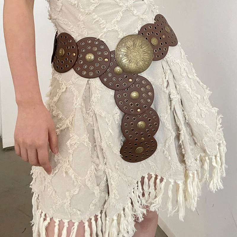 Decorative belt with brown leather and gold studs on a white lace garment.