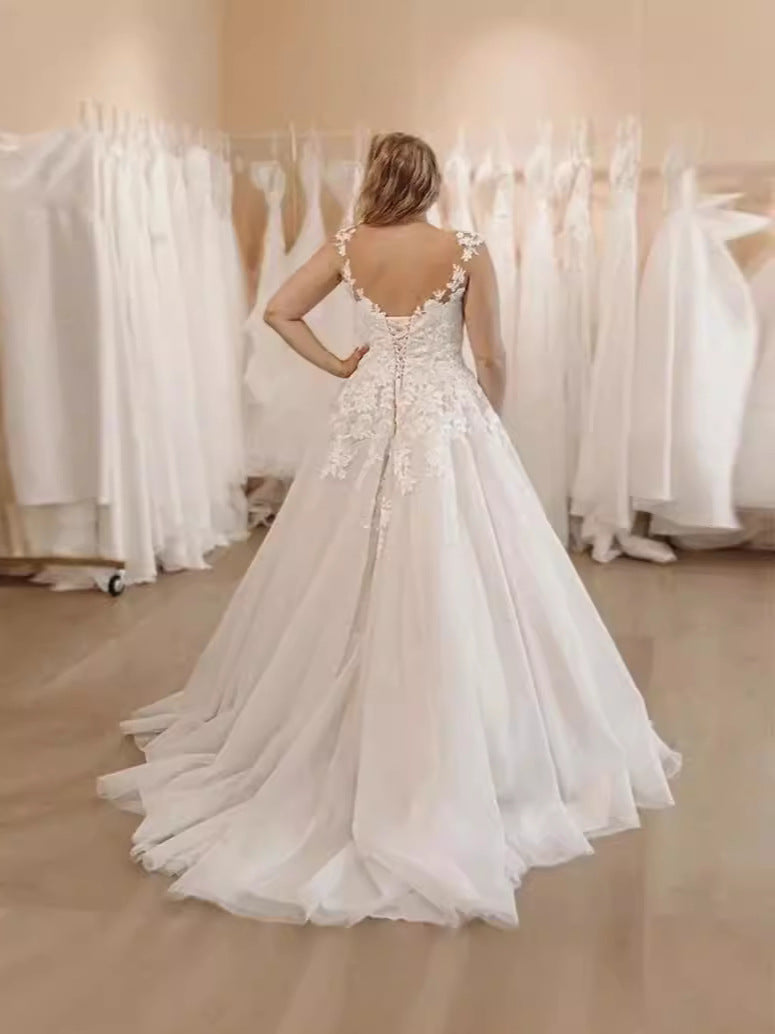 Woman wearing a white wedding dress in a fitting room with mirrors.