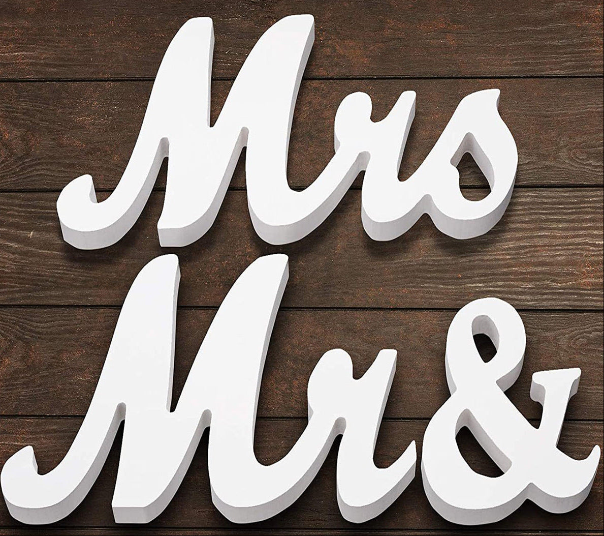 White 'Mrs' and '& ' letters on a wooden background with Christmas decorations.