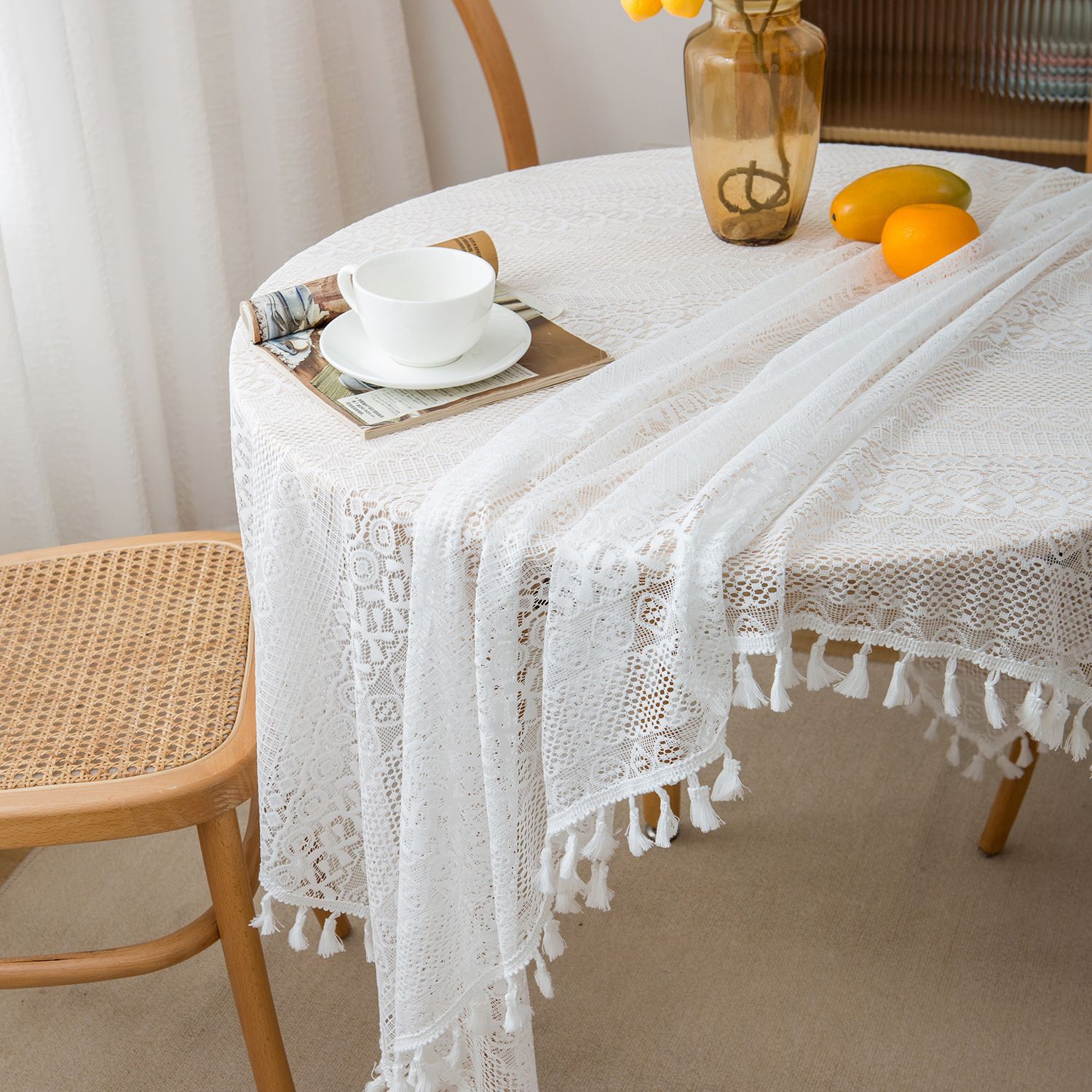 White lace tablecloth on a round table with a cup and saucer, and a vase with flowers.