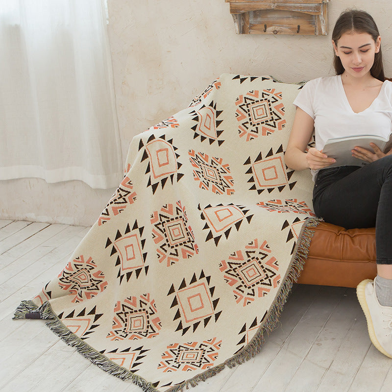 Woman sitting on a couch with a patterned blanket and tablet