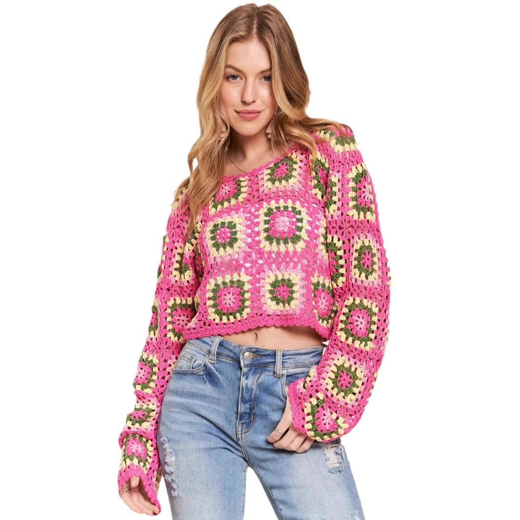 Woman wearing a pink and green patterned sweater with blue jeans on a beige background