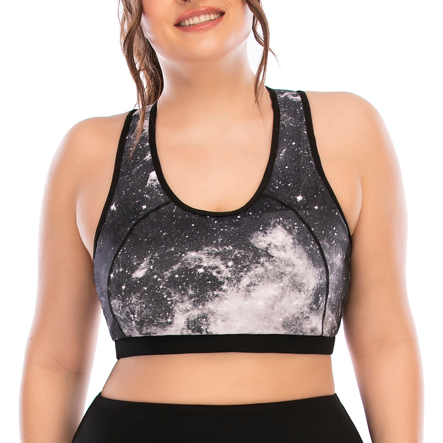 Person wearing a black and white galaxy-patterned sports bra on a white background