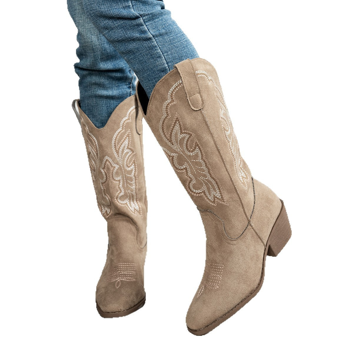 Beige cowboy boots with white embroidery worn with blue jeans on a white background