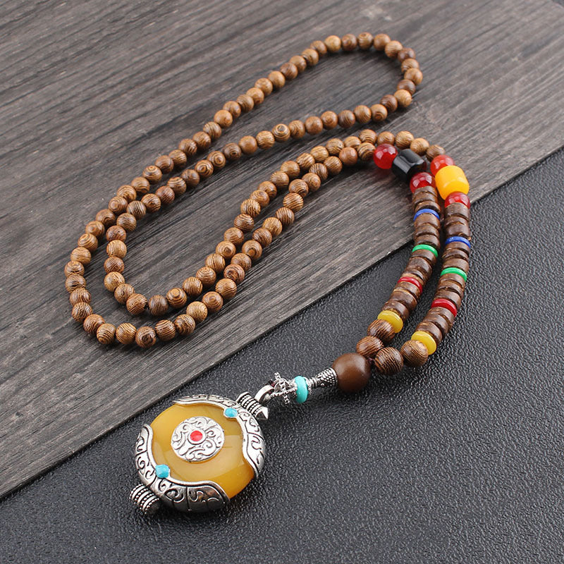Wooden beaded necklace with a yellow pendant on a dark surface