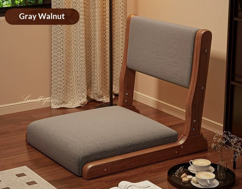 Wooden chair with gray cushion on a wooden floor, surrounded by tea set and decor items.