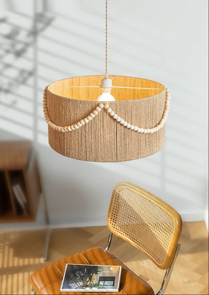Woven pendant light hanging above a chair with a magazine on a wooden floor.