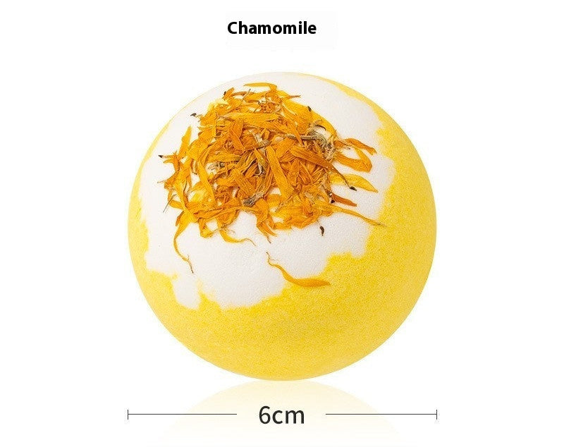 Yellow bath bomb with chamomile flowers on a white background