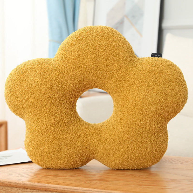 Yellow flower-shaped cushion on a wooden surface with a blurred background