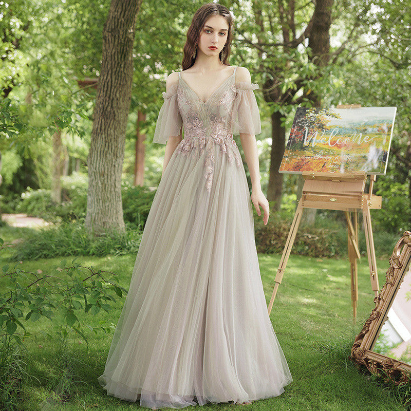 Woman in a light gray dress standing in a garden with a painting easel in the background