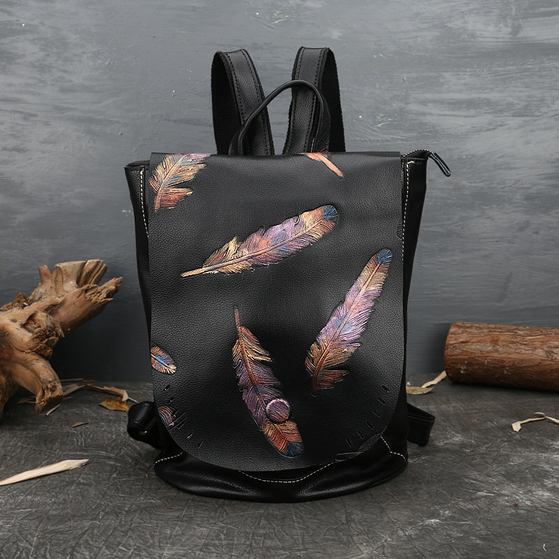 Black backpack with feather design on a dark textured surface