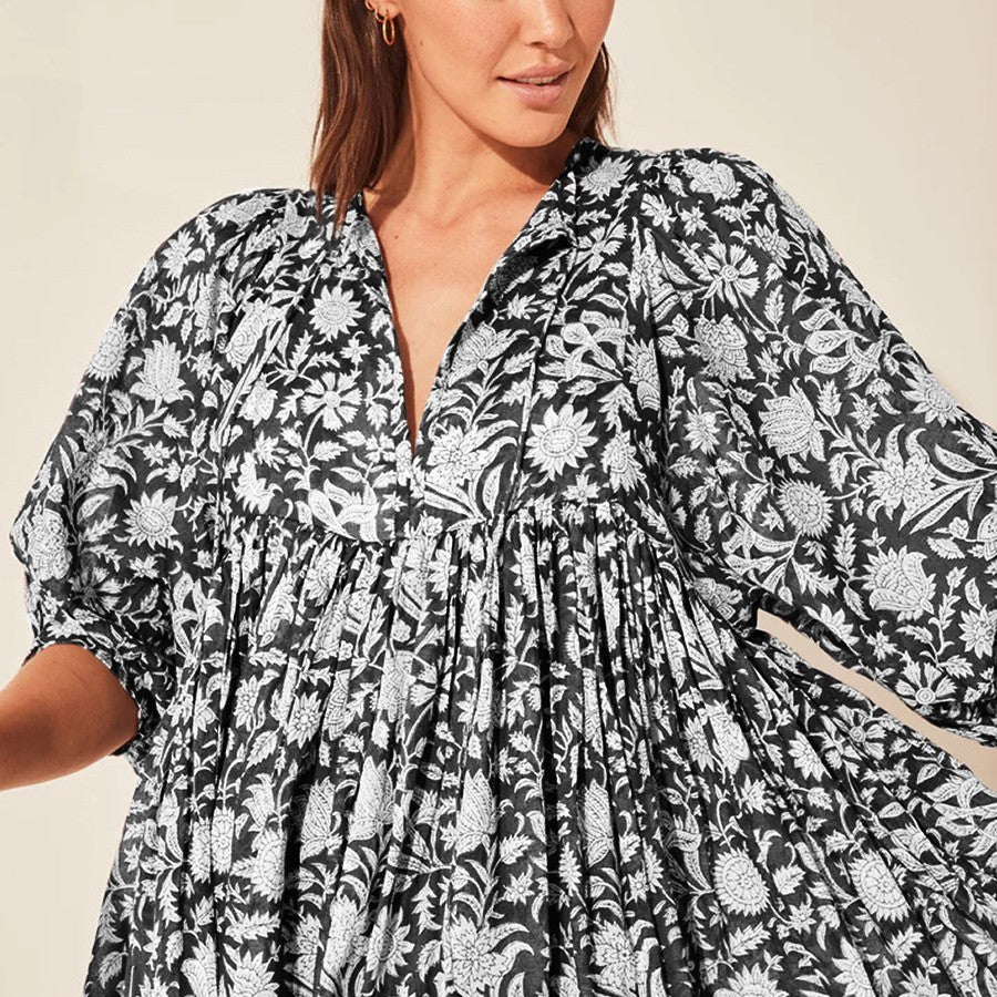 Woman wearing a black and white floral dress against a beige background