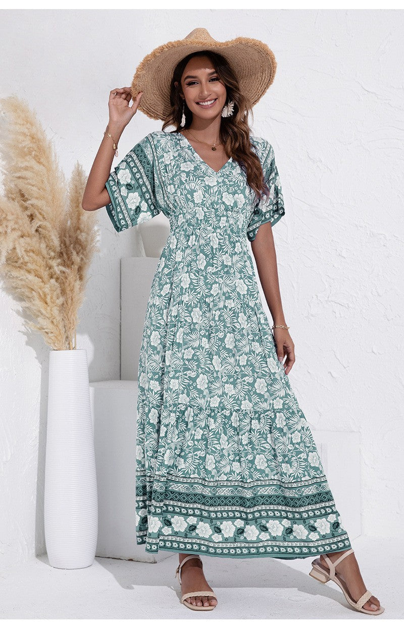 Woman wearing a green floral dress and straw hat against a white background