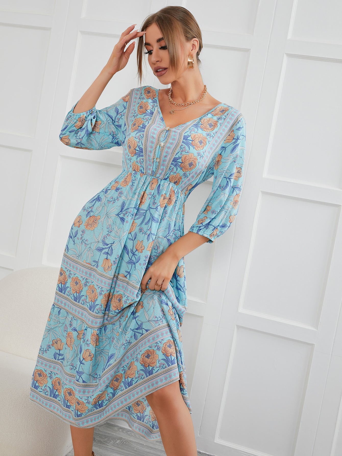 Woman wearing a blue floral dress against a white wall