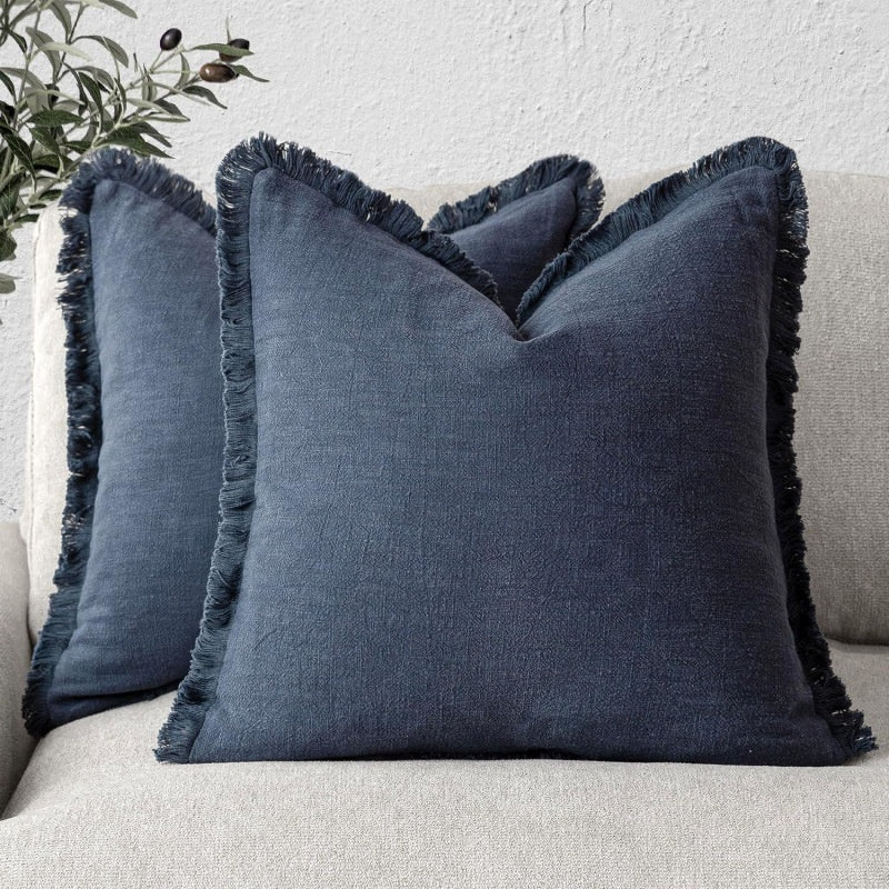 Blue pillows with frayed edges on a light-colored sofa.