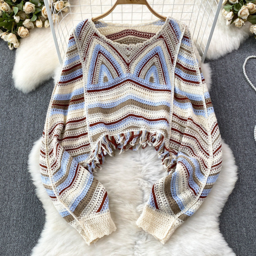 Crocheted cardigan with colorful pattern on a fluffy white surface.