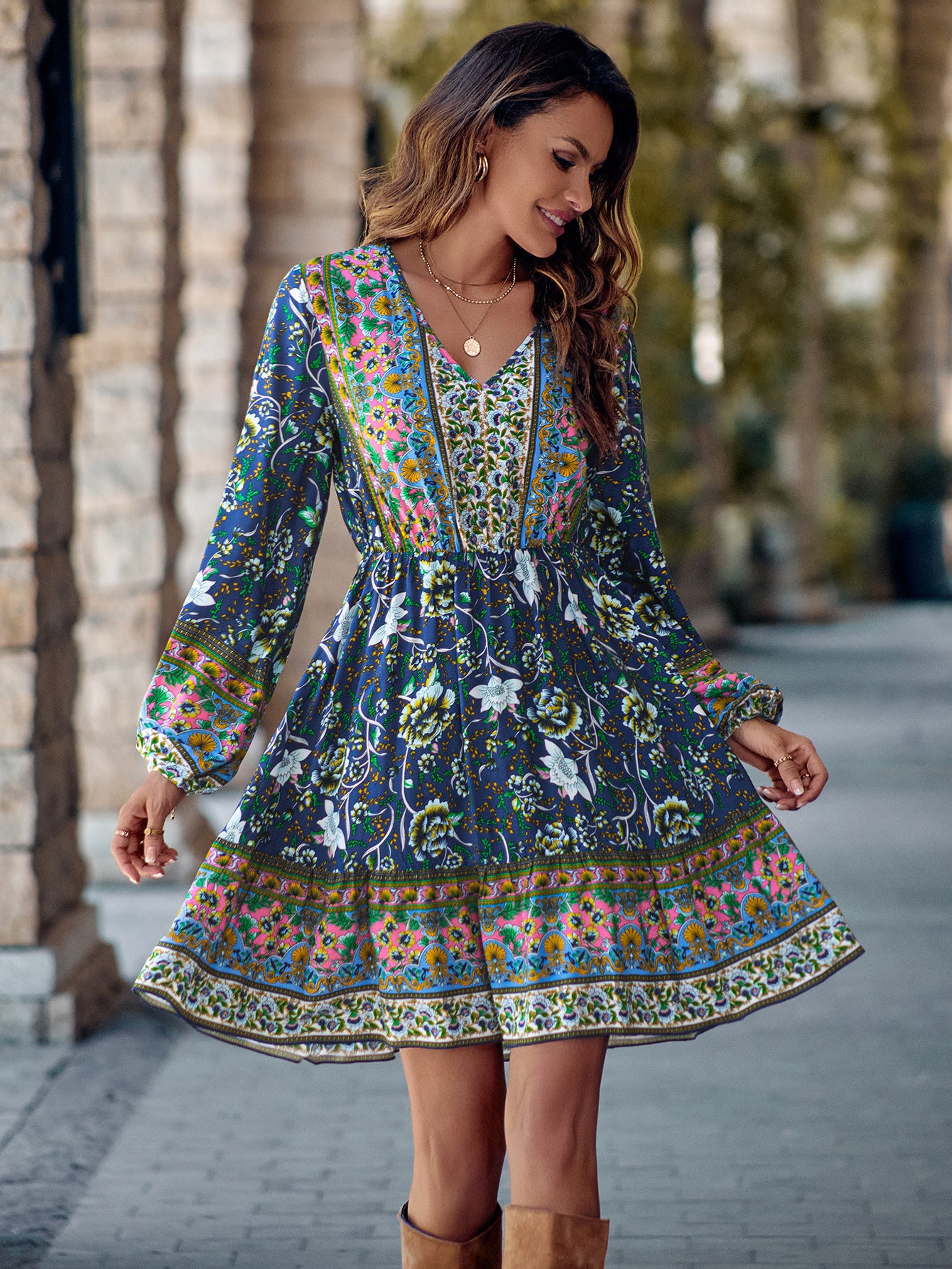 Woman wearing a colorful patterned dress with long sleeves in an outdoor setting.