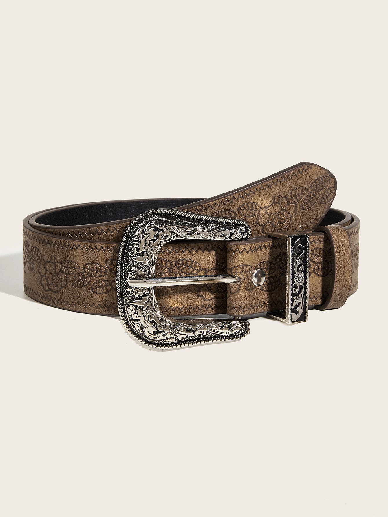 Brown leather belt with intricate design and silver buckle on a beige background