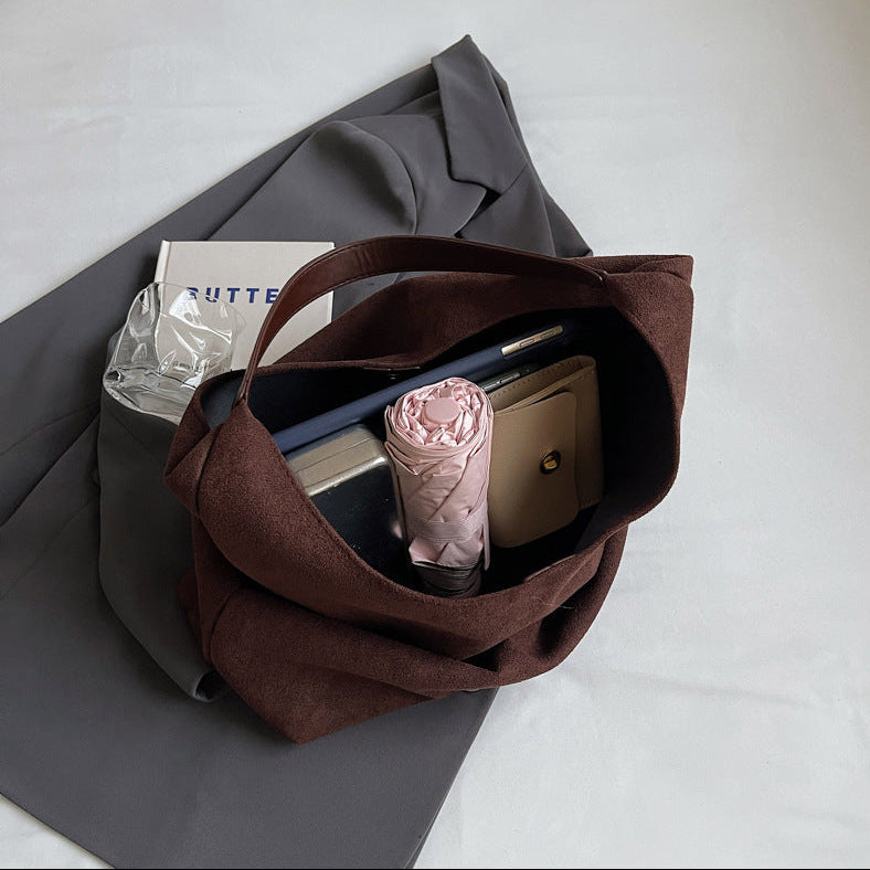 Brown tote bag with items on a gray surface