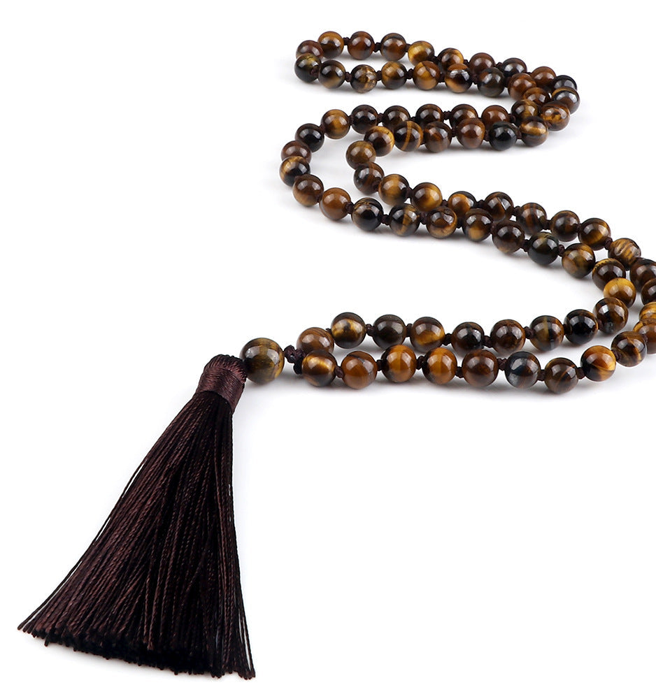 Meditation necklace with brown beads and tassel on a white background
