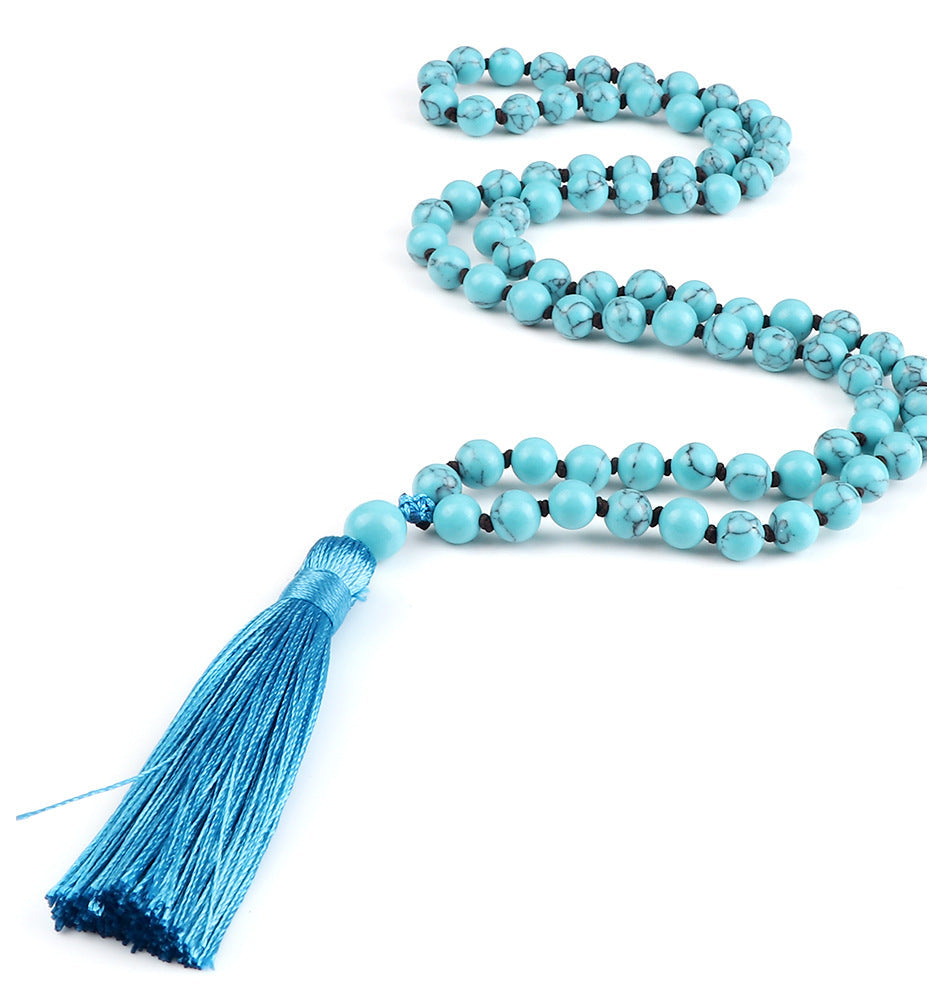 Turquoise beaded necklace with a blue tassel on a white background